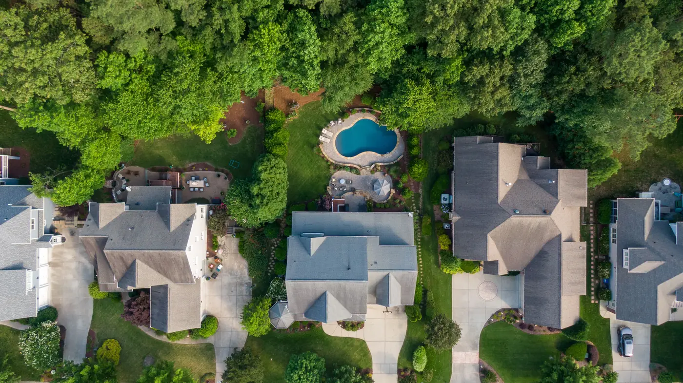 Aerial view of houses on a tree-lined street, with one lot outlined